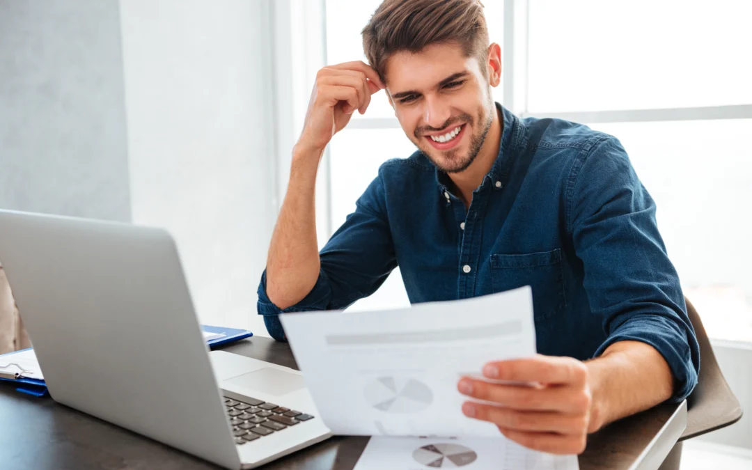 A young man reading Small Business Tax Strategies papers while sitting at a table.